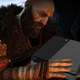 Kratos holds a black PS4 in his large hands.